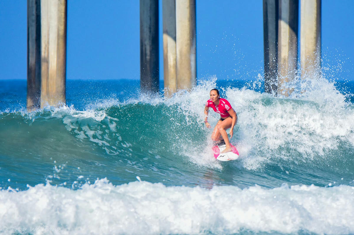 Carissa Moore surfing beside a pier