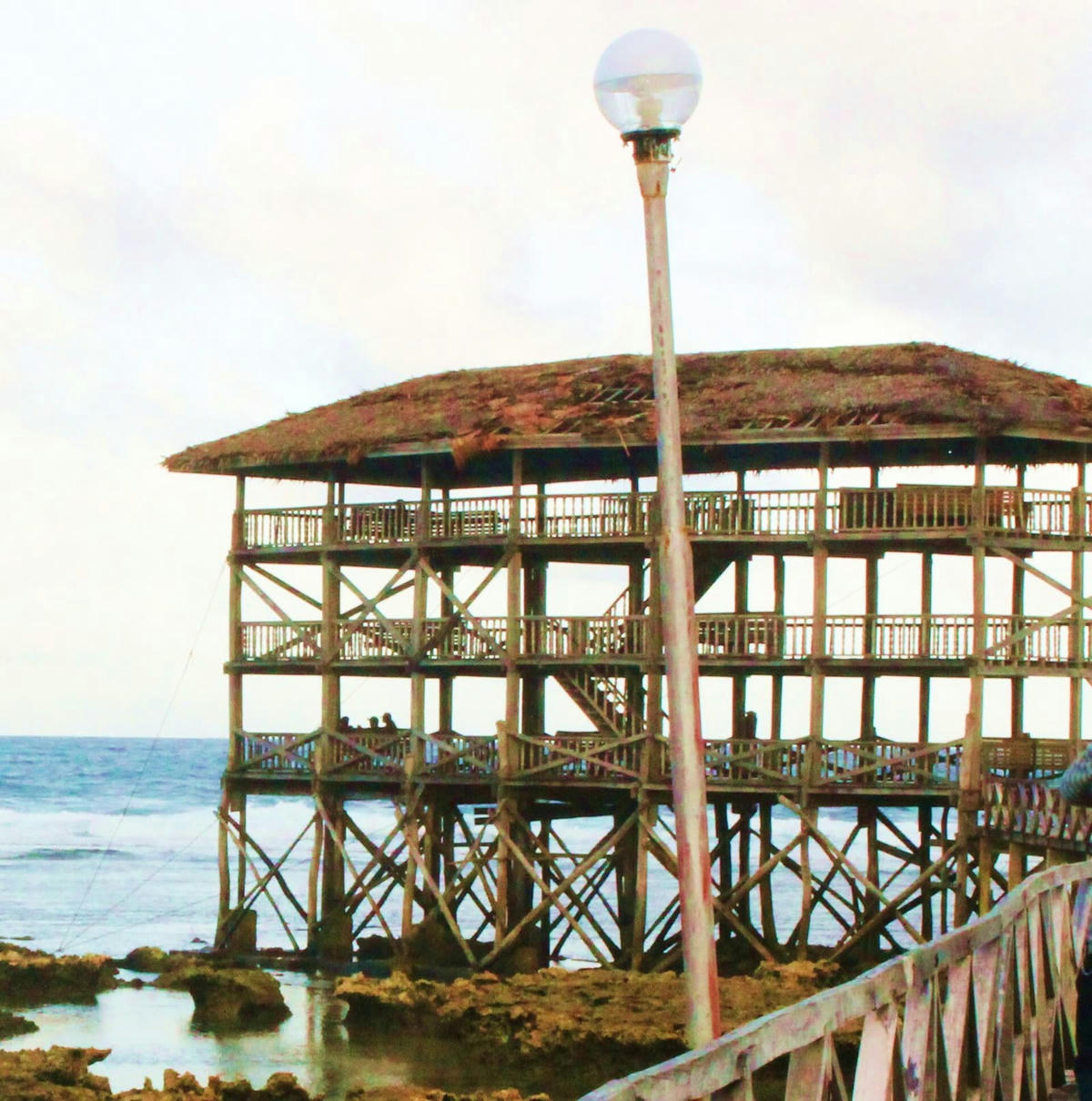 The old wooden judges' tower at Cloud 9 in 2014, with a thatched roof, beside the boardwalk