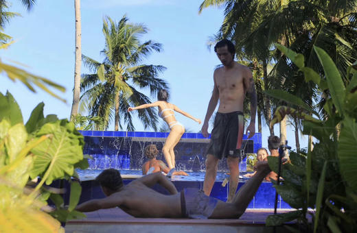 OK Surf instructor and student with a soft-top surfboard on the beach in General Luna, Siargao