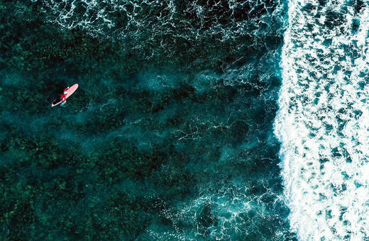 Aerial view of a surfer paddling out over the reef at Siargao