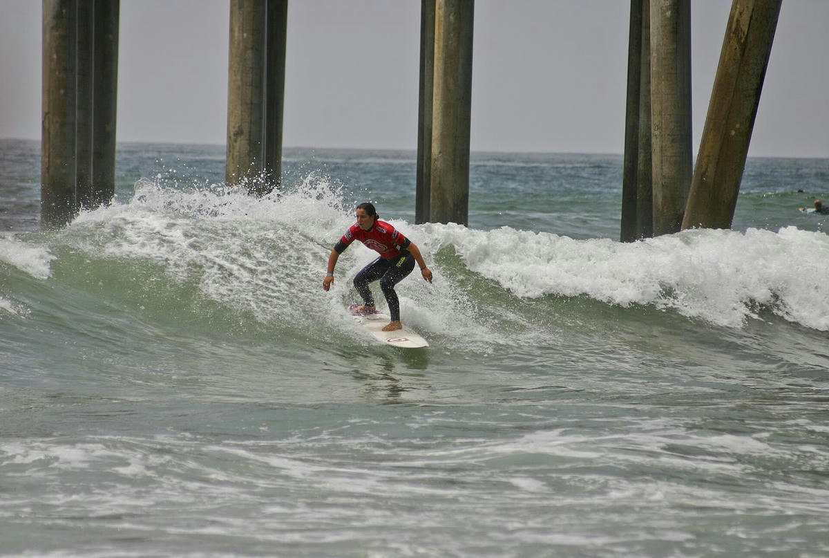 Tyler Wright riding a wave beside a pier